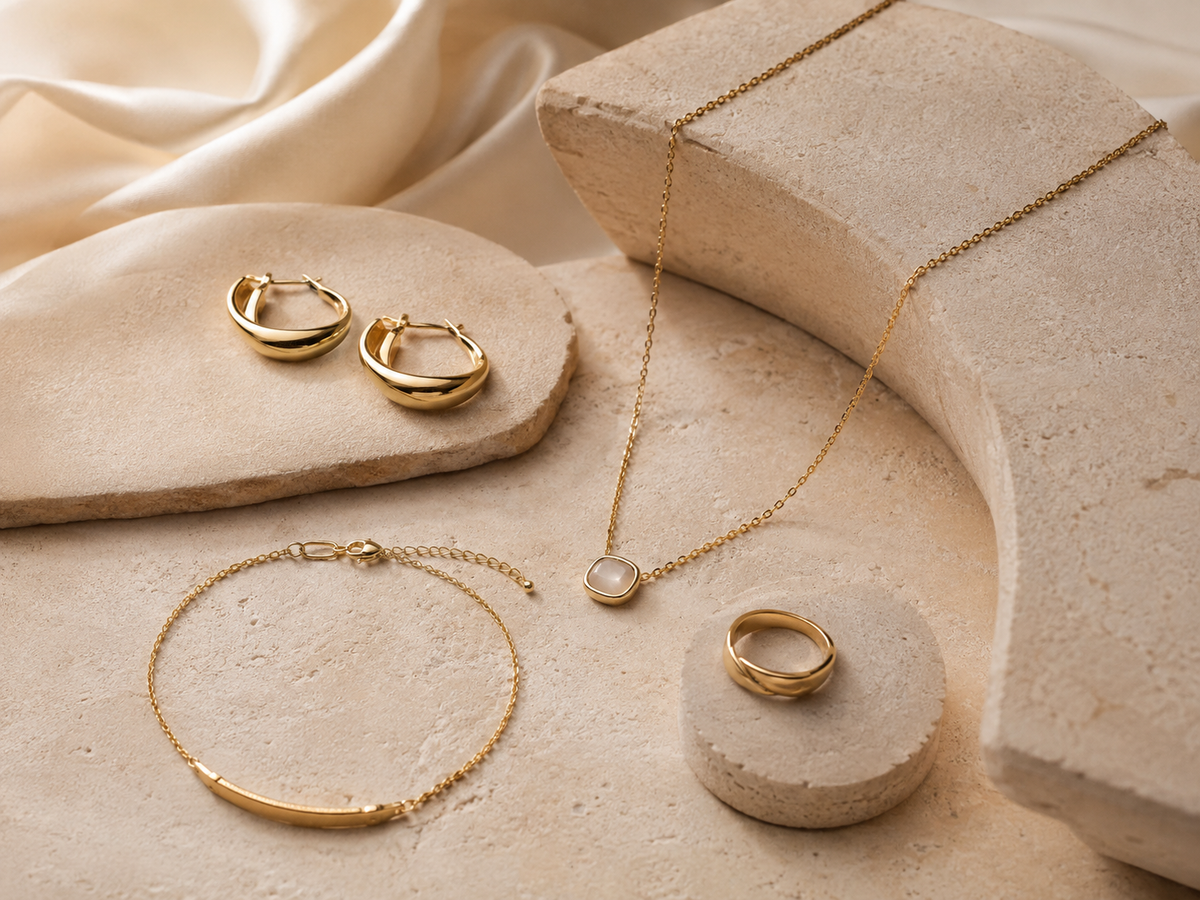 Unbranded gold jewelry on warm ivory stone
